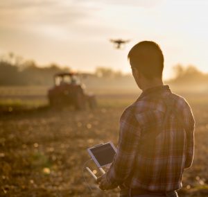 Farmer driving drone above field